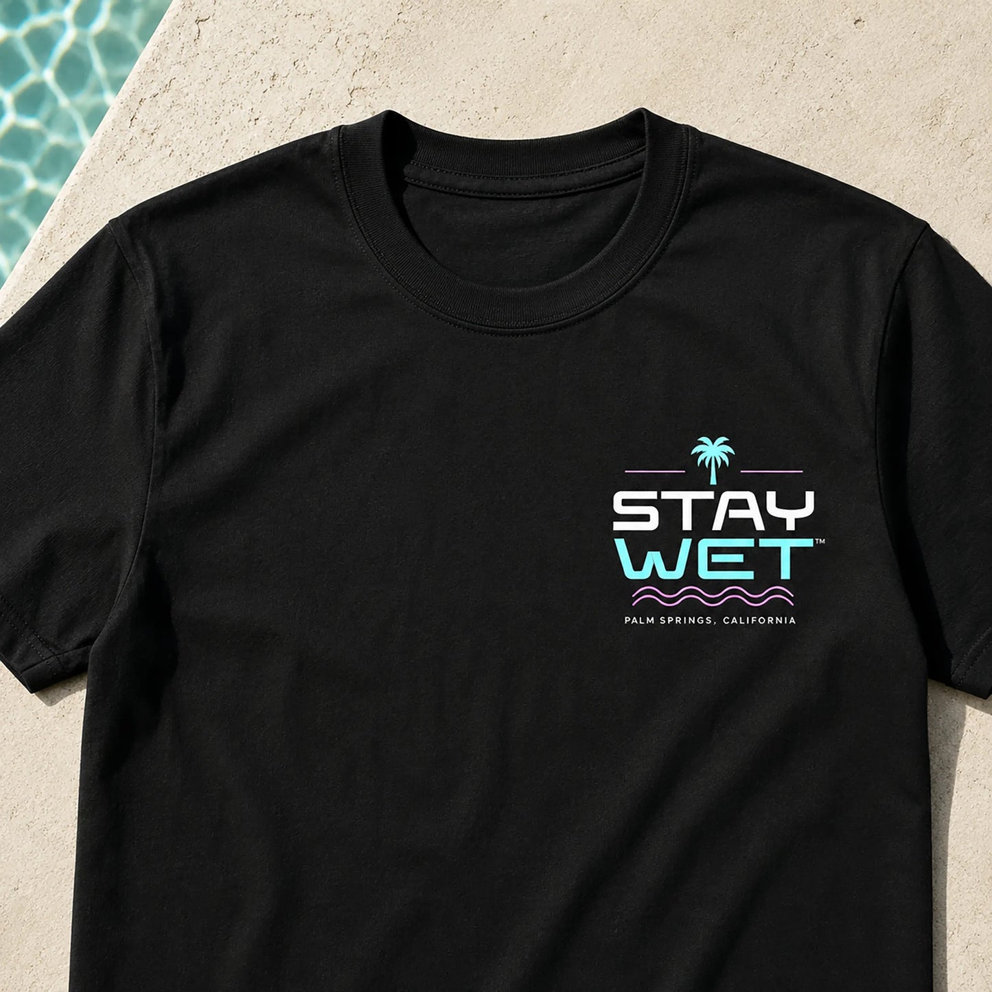 Close-up of the small Poolside Takeover Palm Tree V left-chest print on a black Stay Wet tee